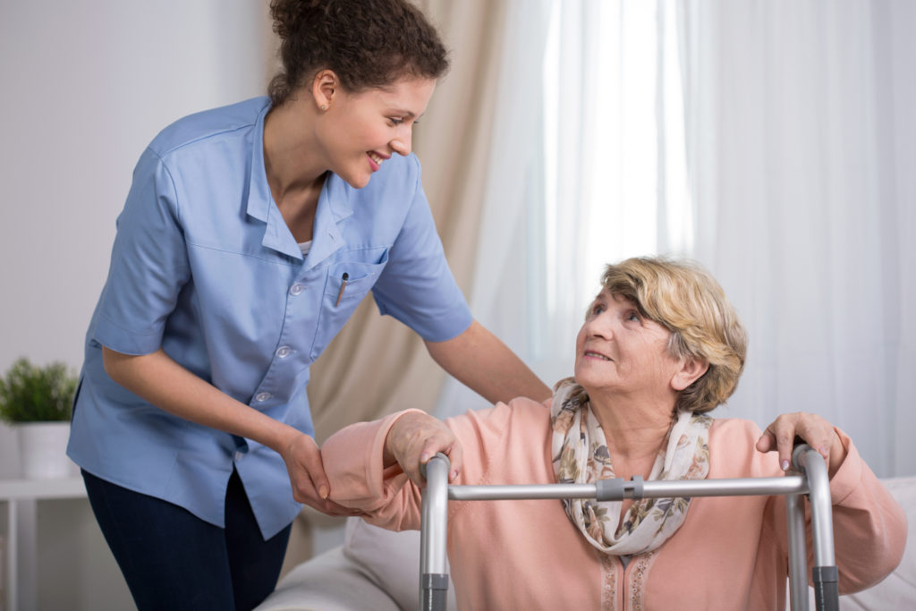 Senior woman using walking frame and supporting nurse